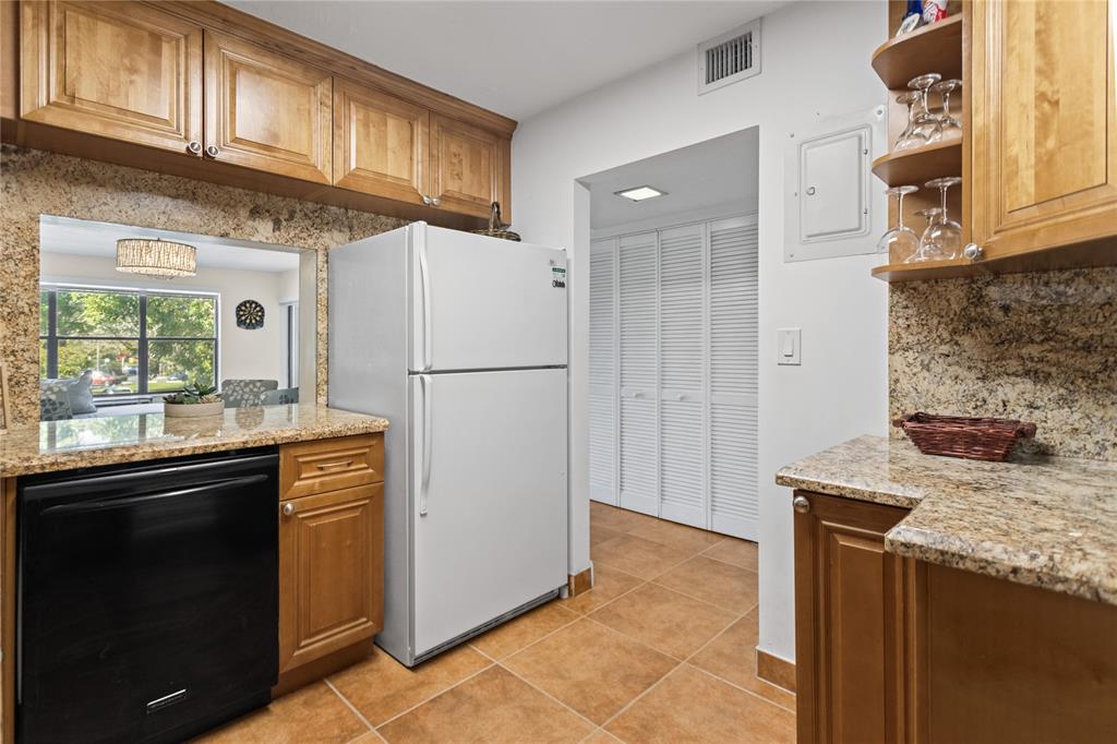 2312 South Cypress Bend Drive, Unit 205 Pompano Beach, FL 33069 - Photo 15 of 61 a kitchen with granite countertop a refrigerator stove and microwave