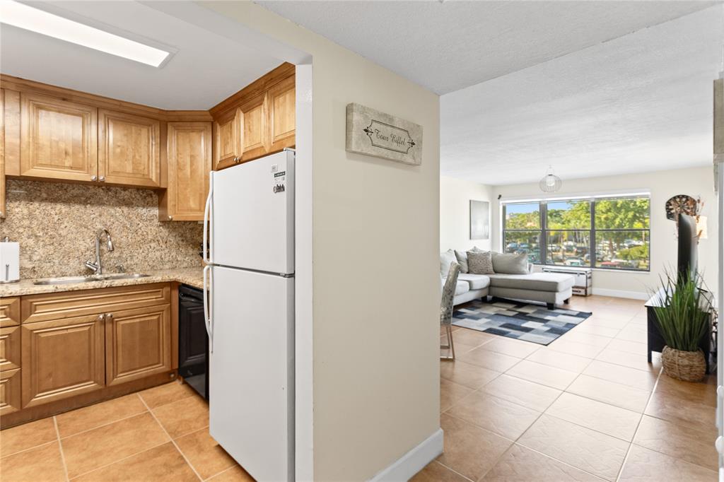 2312 South Cypress Bend Drive, Unit 205 Pompano Beach, FL 33069 - Photo 18 of 61 a kitchen with a refrigerator a stove a sink and a window