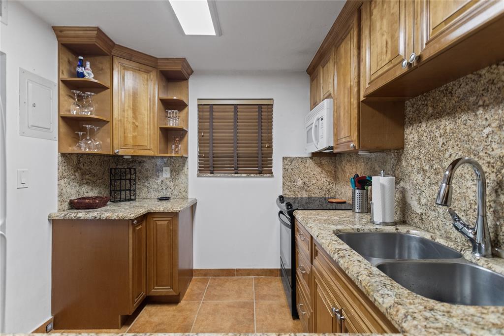 2312 South Cypress Bend Drive, Unit 205 Pompano Beach, FL 33069 - Photo 19 of 61 a kitchen with stainless steel appliances granite countertop a sink stove and refrigerator