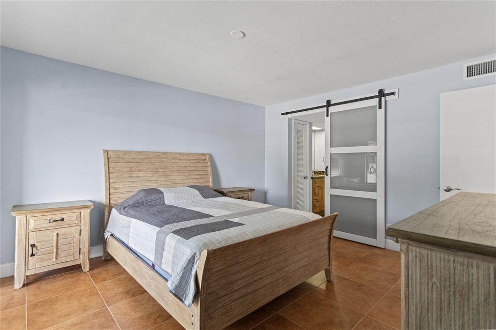 2312 South Cypress Bend Drive, Unit 205 Pompano Beach, FL 33069 - Photo 34 of 61 a bedroom with a bed and cabinets