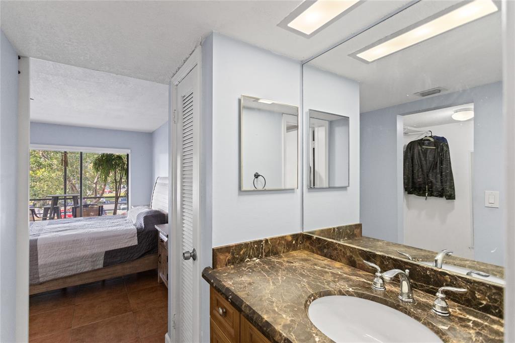2312 South Cypress Bend Drive, Unit 205 Pompano Beach, FL 33069 - Photo 40 of 61 a en suite bathroom with a granite countertop sink and a mirror