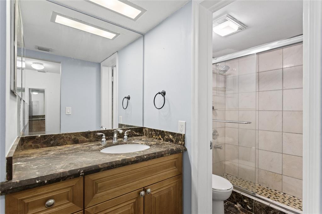 2312 South Cypress Bend Drive, Unit 205 Pompano Beach, FL 33069 - Photo 5 of 61 a bathroom with a granite countertop sink a mirror and a shower