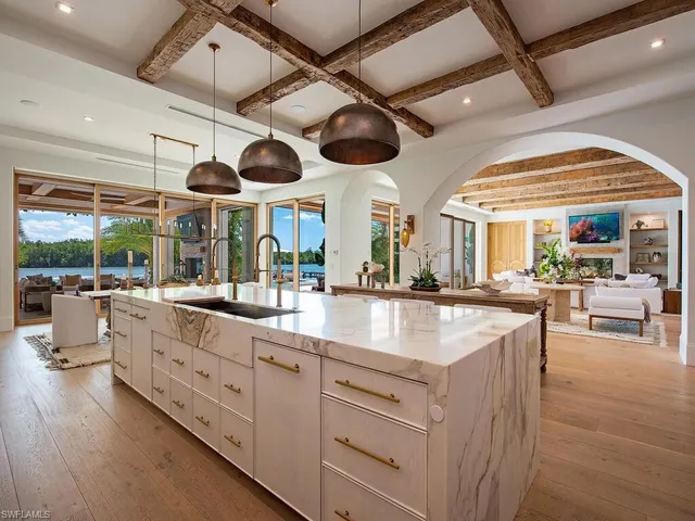 a kitchen with stainless steel appliances a large counter space a large window and chandelier