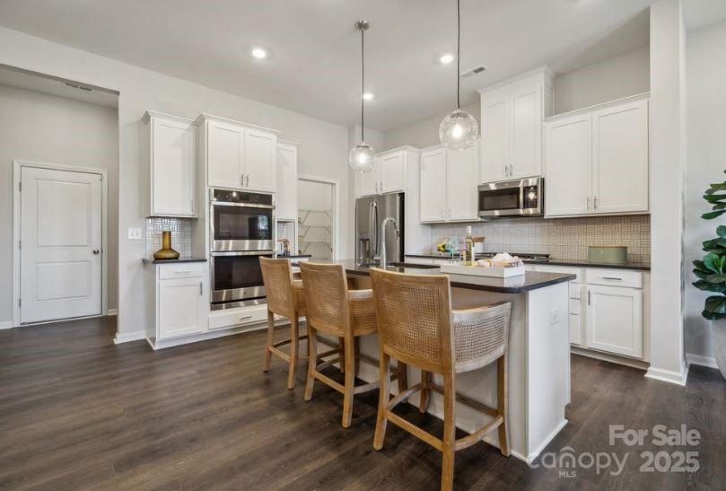 8664 Miles Gap Road Indian Land, SC 29707 - Photo 6 of 29 a kitchen with stainless steel appliances granite countertop a refrigerator a stove top oven a sink dishwasher and white cabinets with wooden floor