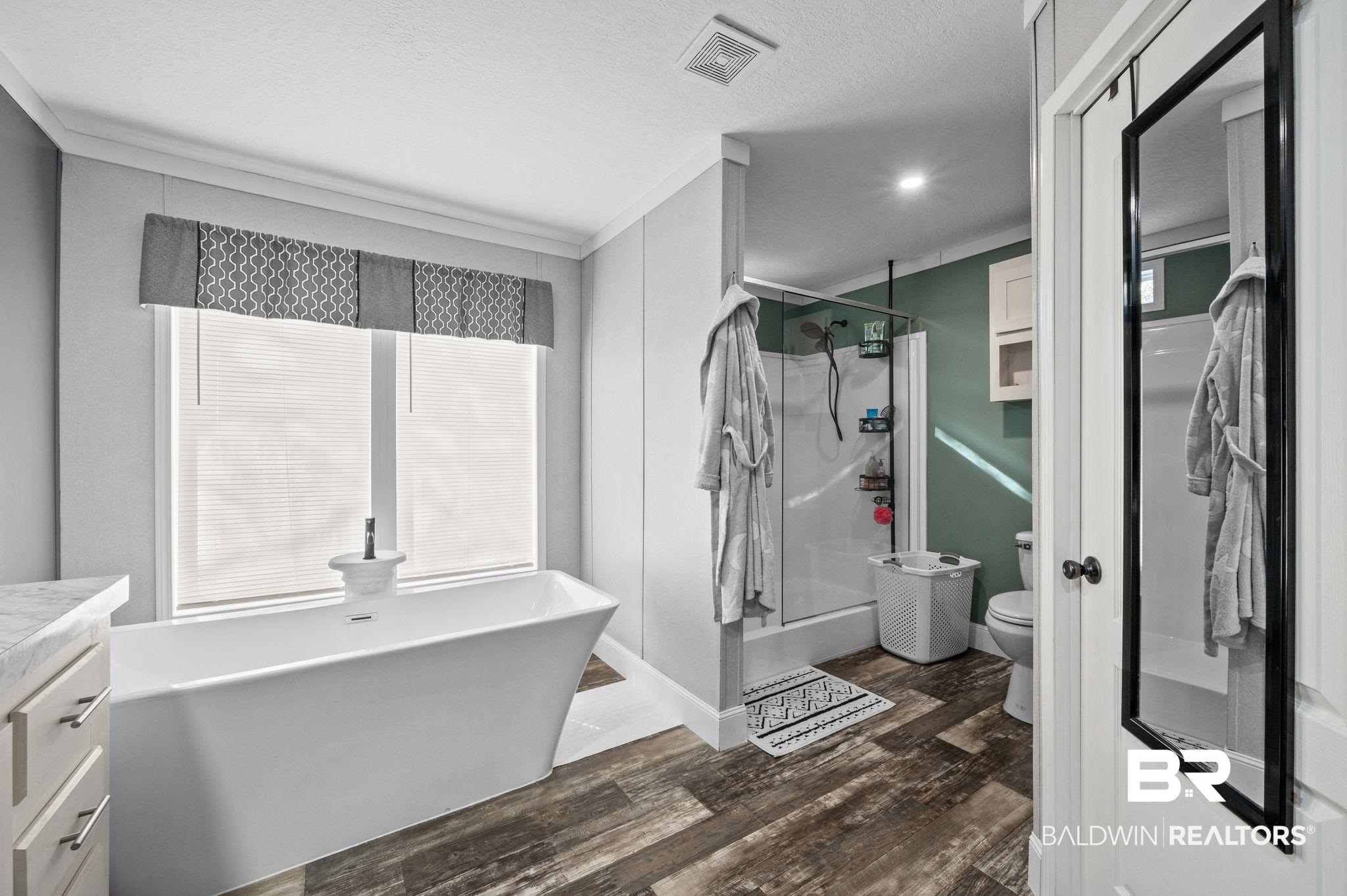 9382 D'Olive Street Bay Minette, AL 36507 - Photo 10 of 27 Full bathroom with vanity, crown molding, wood-type flooring, plus walk in shower, and toilet