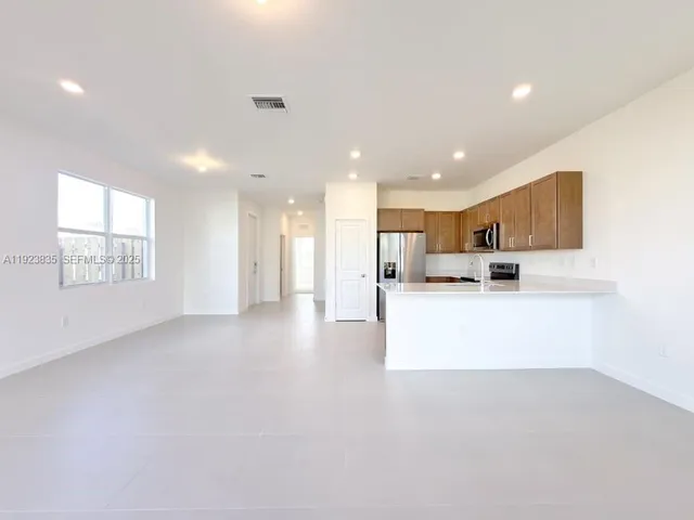 a view of kitchen with kitchen island a sink wooden floor and a refrigerator
