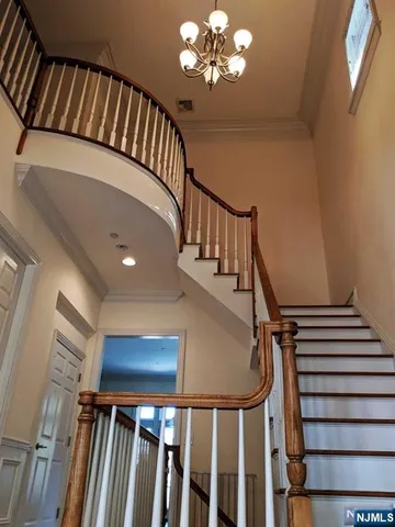 a view of staircase with railing pendant lights and wooden floor