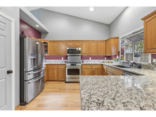 a kitchen with stainless steel appliances granite countertop a stove a sink and a microwave
