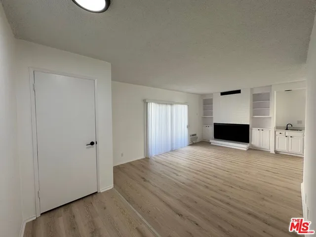 a view of empty room with wooden floor and fireplace