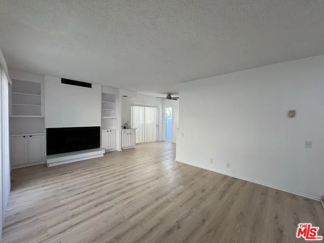 a view of empty room with wooden floor and fireplace