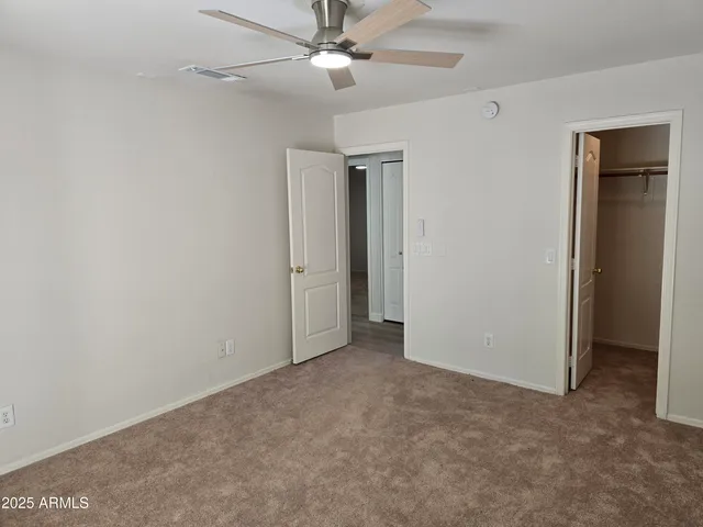 an empty room with closet and a ceiling fan