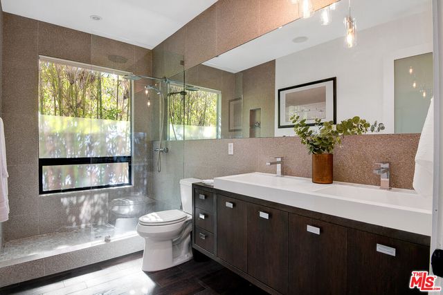 a bathroom with a granite countertop sink a toilet a mirror and a window