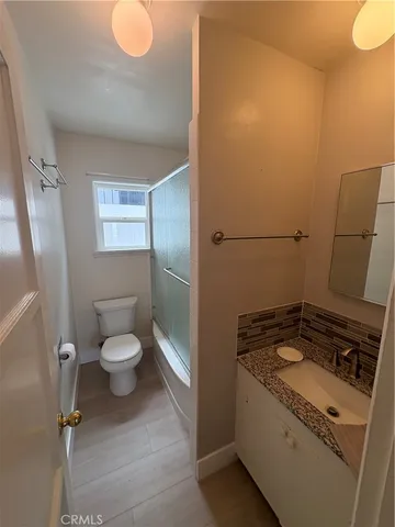 a bathroom with a granite countertop sink and a toilet