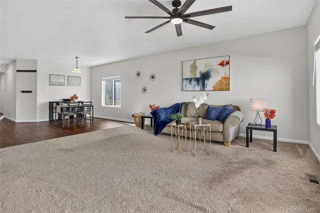 a living room with furniture and a dining table with kitchen appliances