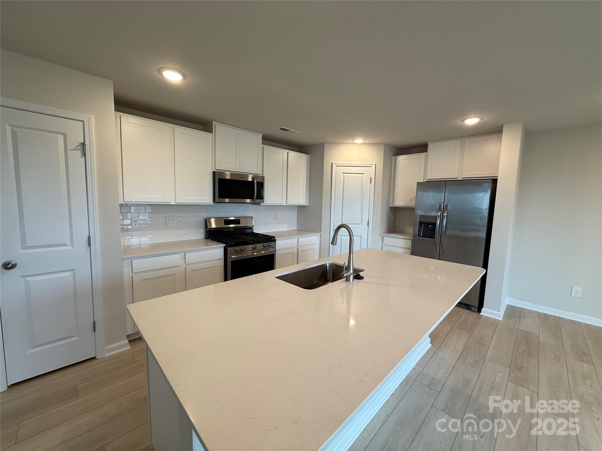 117 Dorian Place Troutman, NC 28166 - Photo 11 of 31 a kitchen with granite countertop a refrigerator a sink a stove a microwave and cabinets