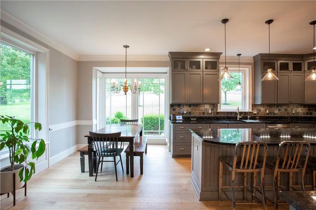 a kitchen with stainless steel appliances granite countertop a stove top oven a dining table and chairs with wooden floor