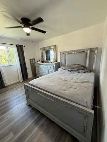 a spacious bedroom with a bed a mirror and a flat tv screen on dresser