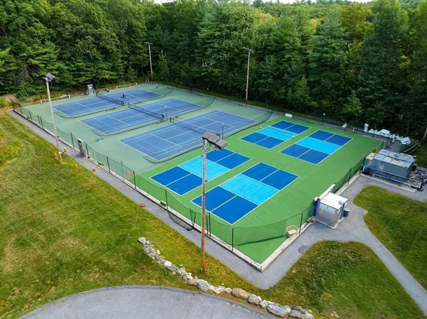 a view of a tennis ground with large trees