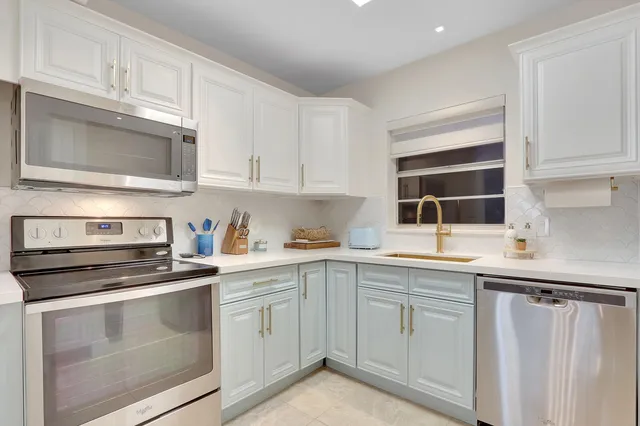 a kitchen with cabinets stainless steel appliances and sink