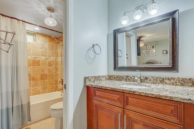 a bathroom with a granite countertop sink toilet and mirror