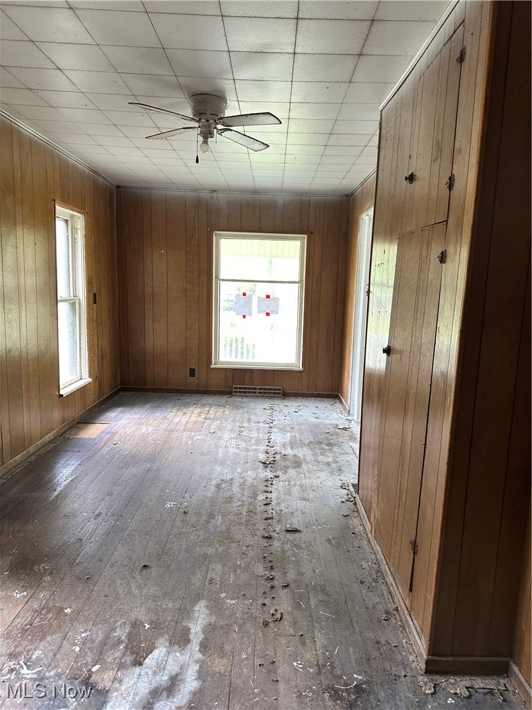 6144 Jefferson Road Ashtabula, OH 44004 - Photo 4 of 30 Empty room with hardwood / wood-style flooring, a ceiling fan, plenty of natural light, and wood walls