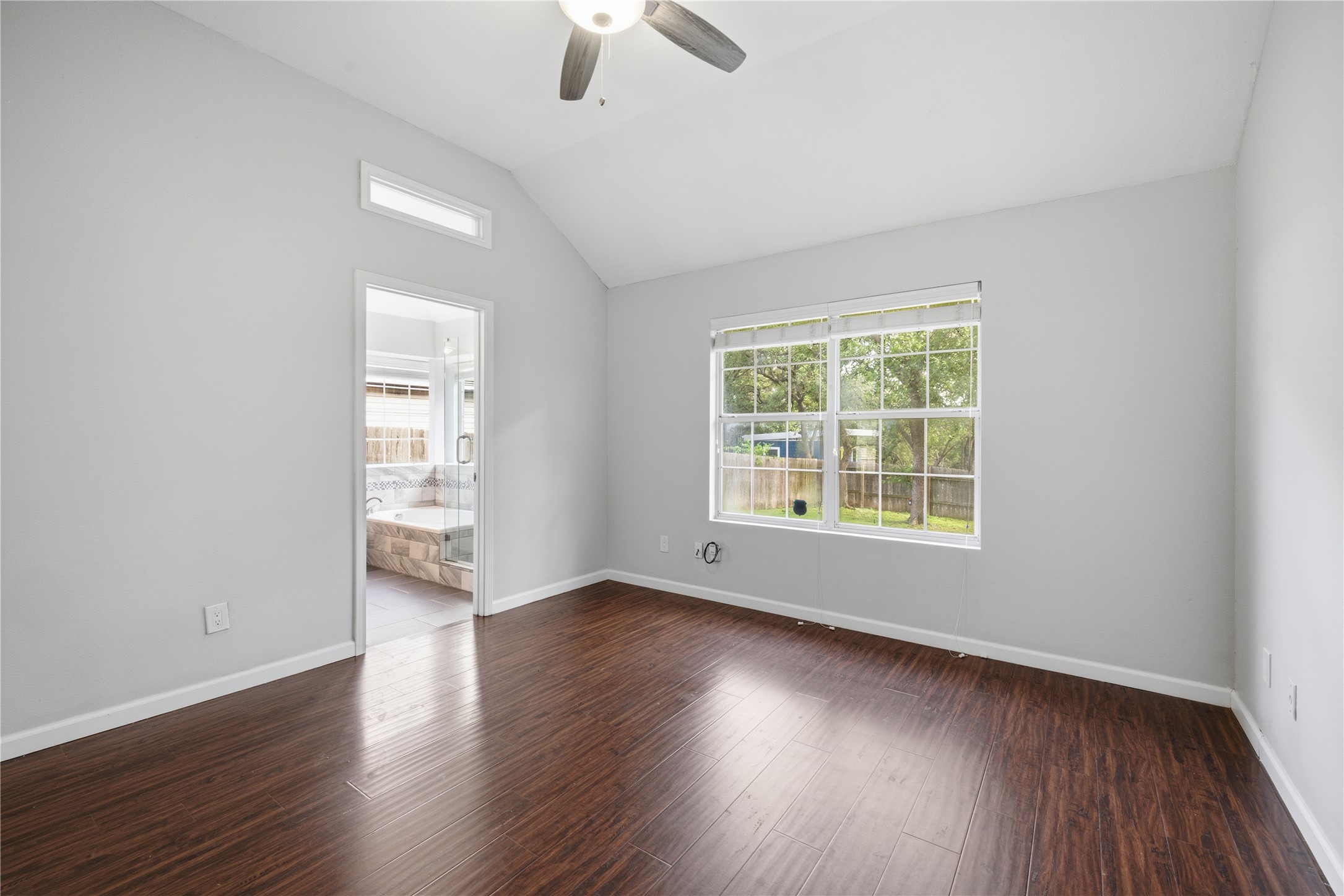 2922 Wickersham Lane Austin, TX 78741 - Photo 4 of 26 an empty room with wooden floor chandelier fan and windows