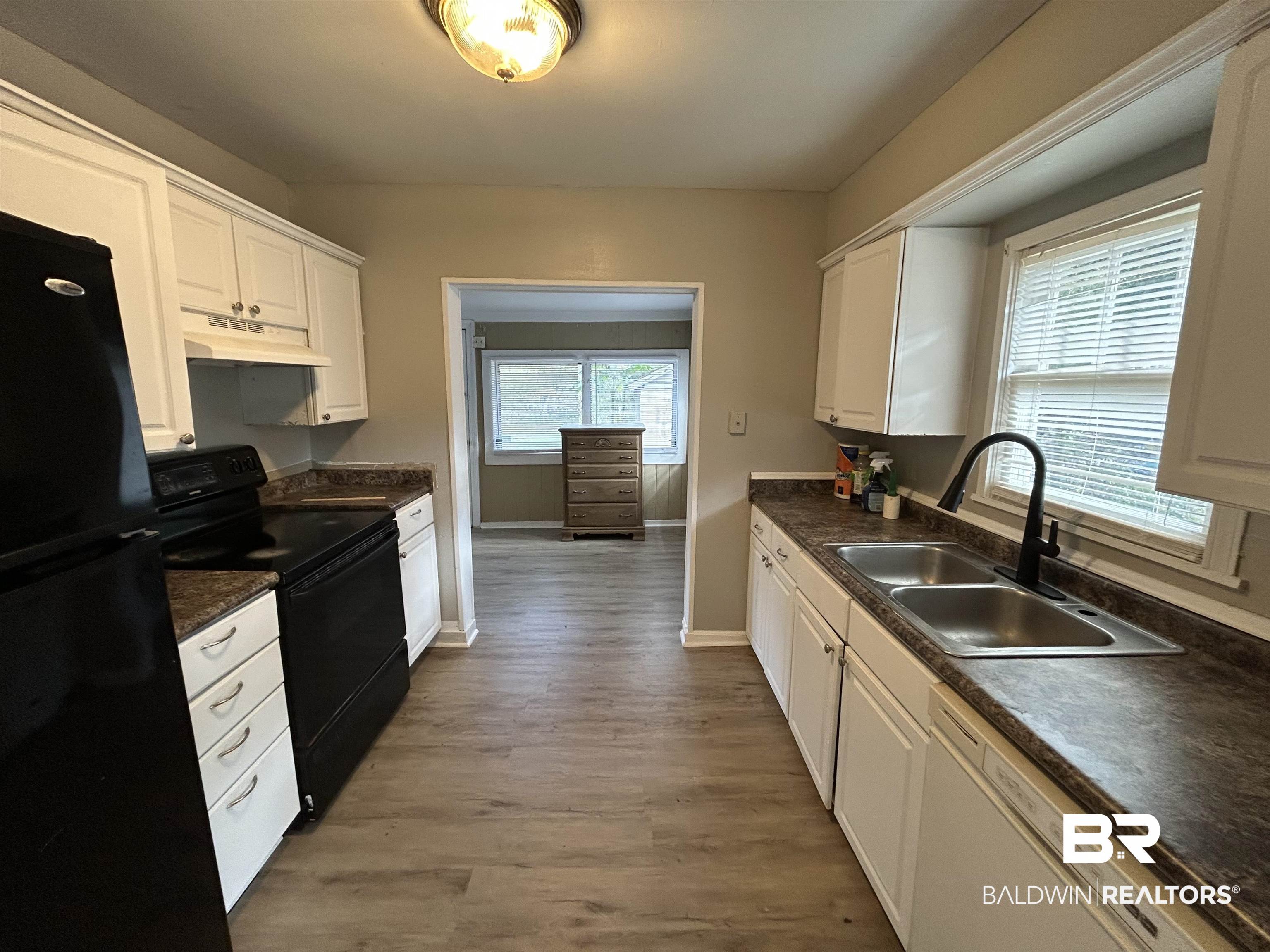2119 Hoppin Street Mobile, AL 36605 - Photo 17 of 23 Kitchen featuring a wealth of natural light, sink, white cabinets, black appliances, and hardwood / wood-style flooring
