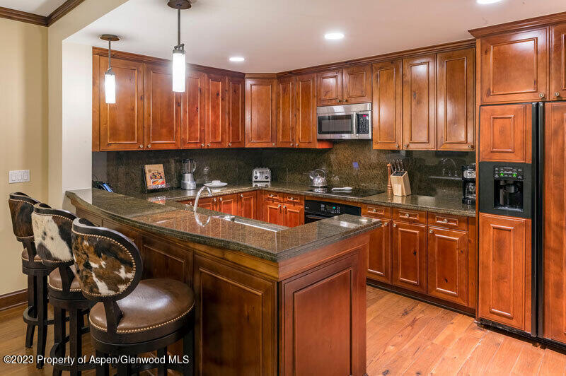 a kitchen with stainless steel appliances granite countertop a sink a stove a refrigerator cabinets and chairs