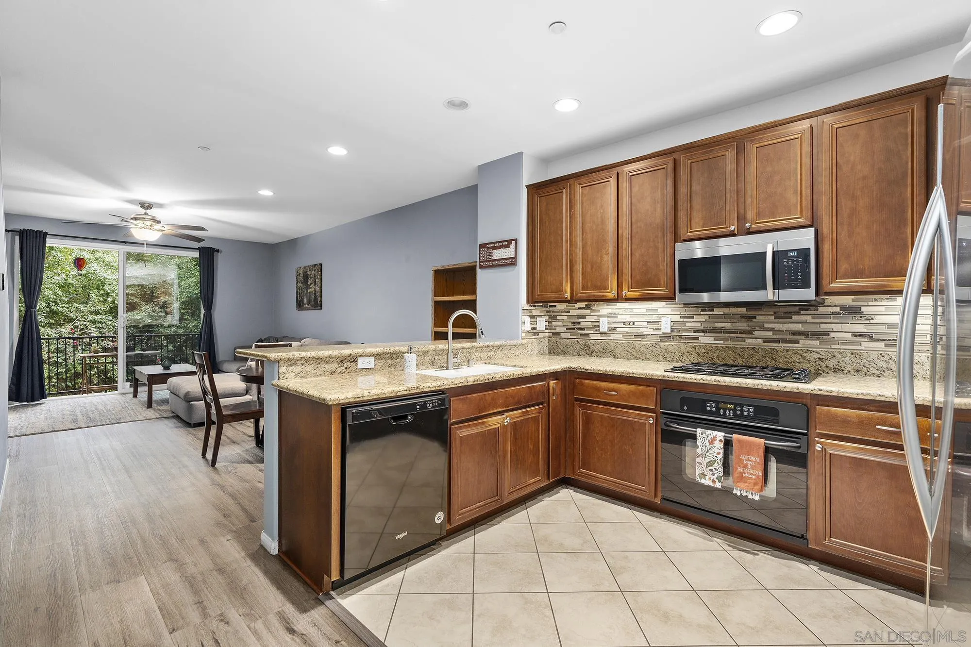 a kitchen with stainless steel appliances granite countertop wooden cabinets a sink dishwasher a stove and a refrigerator with wooden floor