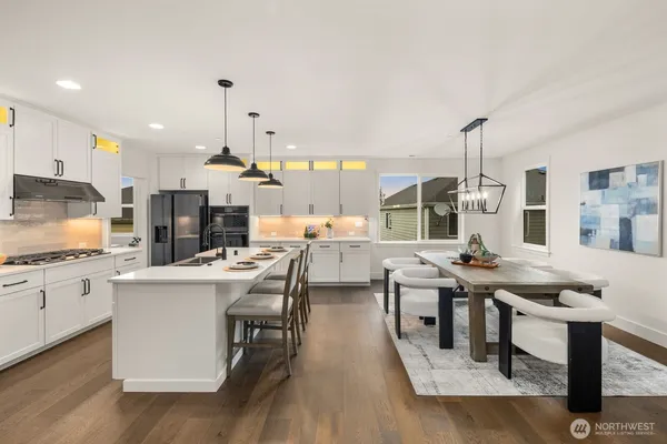 a kitchen with stainless steel appliances kitchen island granite countertop a stove and white cabinets