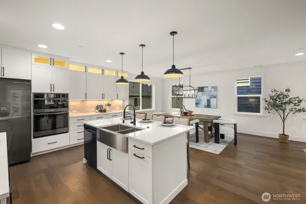 a kitchen with stainless steel appliances kitchen island a stove a sink a oven a dining table and chairs
