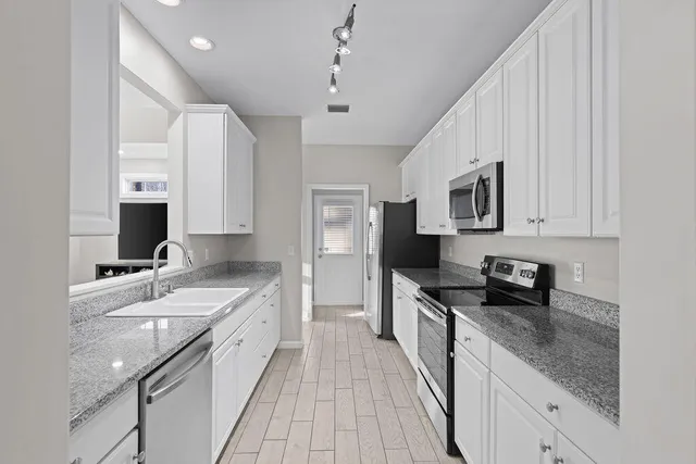 a kitchen with stainless steel appliances granite countertop a sink stove and refrigerator