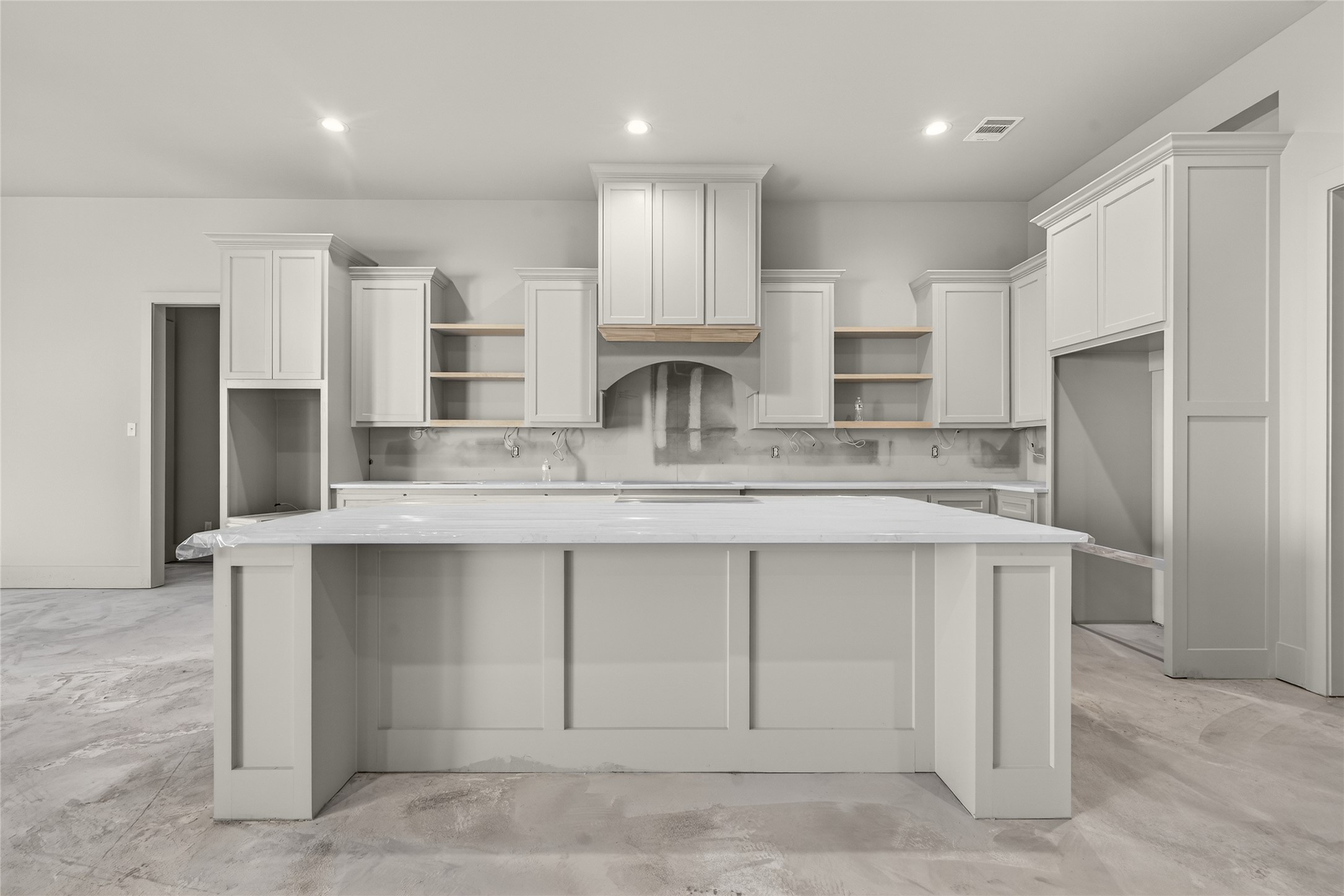 a kitchen with kitchen island granite countertop a stove top oven a sink and cabinets