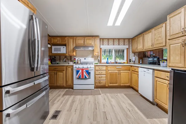 a kitchen with stainless steel appliances kitchen island granite countertop a stove a sink dishwasher and a refrigerator
