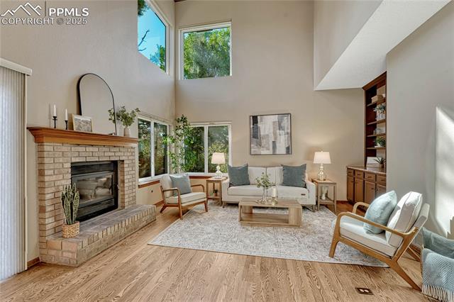 Family room with vaulted ceilings, a fireplace, built-in shelving and cabinetry with a quartzite countertop, and hardwood flooring
