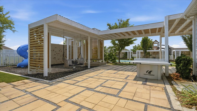 2038 East Ranch Road Eagle Mountain, UT 84005 - Photo 45 of 66 Expansive outdoor area featuring a patterned paver patio, a white pergola structure with wood slat accents, and a dedicated play space with a blue slide and swing set