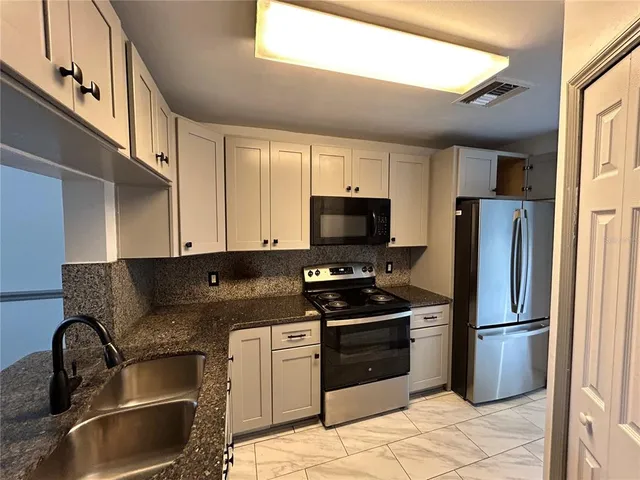 a kitchen with stainless steel appliances granite countertop a refrigerator a stove a sink and a microwave