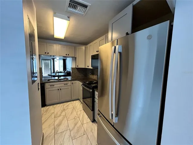 a kitchen with stainless steel appliances a refrigerator sink and microwave