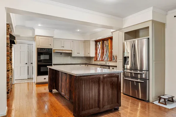 a kitchen with stainless steel appliances granite countertop a sink and a white cabinets with wooden floor