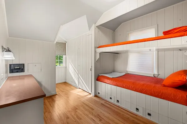 a view of a bedroom with wooden floor and window