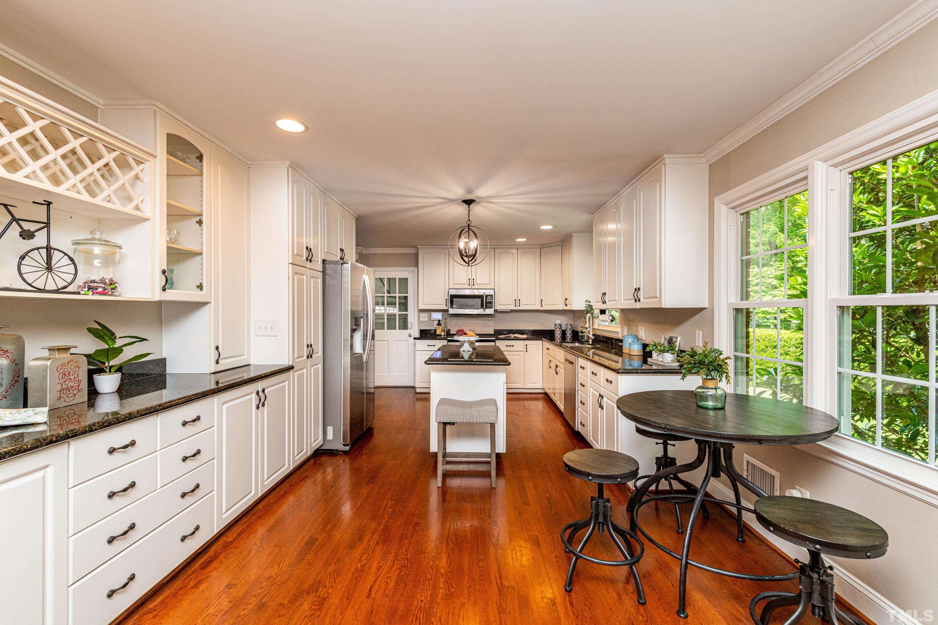 201 Chatterson Drive Raleigh, NC 27615 - Photo 10 of 44 a kitchen with stainless steel appliances kitchen island wooden floors and white cabinets