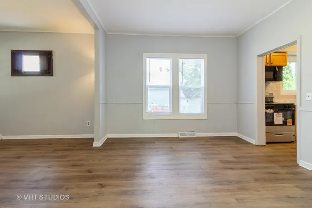 a view of an empty room with window and wooden floor
