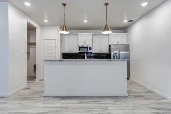 a view of a kitchen with center island stainless steel appliances wooden floor and window
