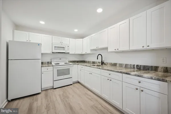 a kitchen with white cabinets white stainless steel appliances and sink