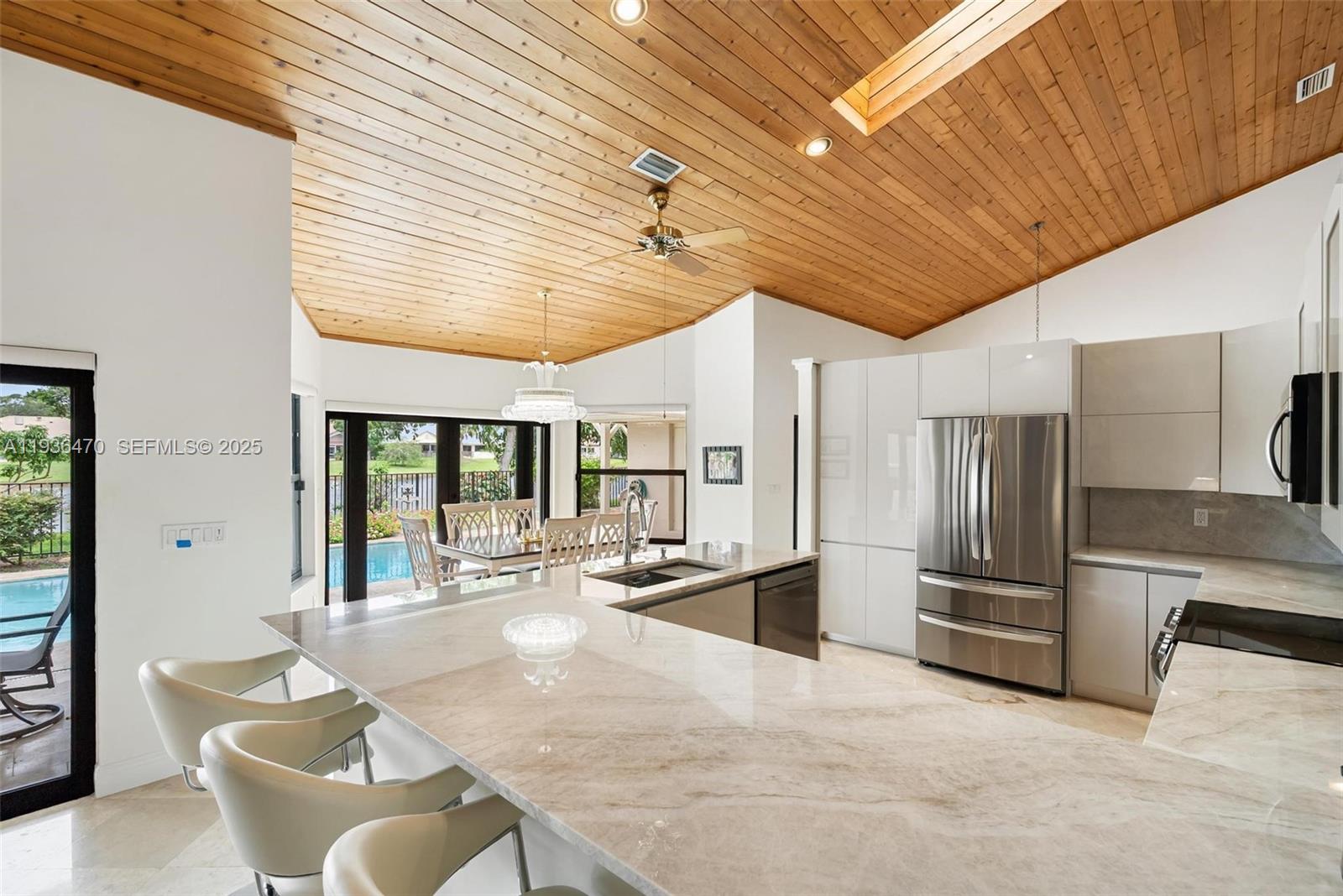 2685 Northwest 27th Terrace Boca Raton, FL 33434 - Photo 8 of 31 a kitchen with stainless steel appliances kitchen island granite countertop a table chairs and a refrigerator