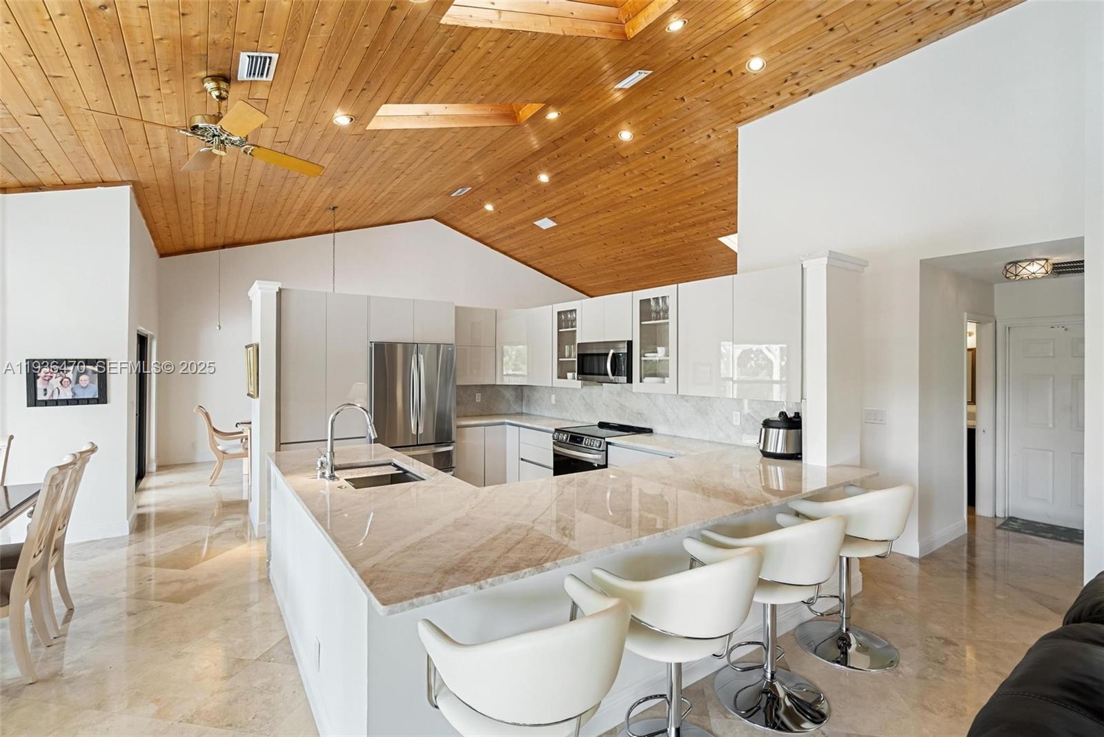 2685 Northwest 27th Terrace Boca Raton, FL 33434 - Photo 9 of 31 a kitchen with stainless steel appliances kitchen island granite countertop a table chairs and a refrigerator