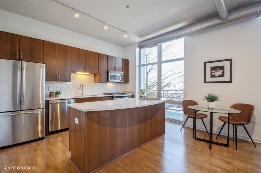 700 North Larrabee Street, Unit 115 Chicago, IL 60654 - Photo 4 of 11 a kitchen with stainless steel appliances granite countertop a stove a refrigerator a sink a dining table and chairs with wooden floor