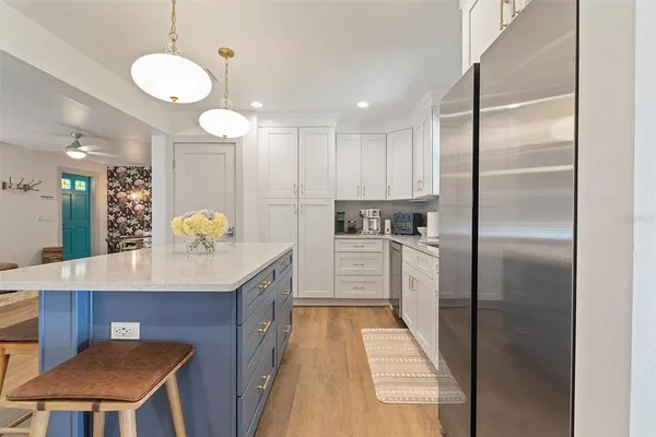 a kitchen with kitchen island a counter top space a sink stainless steel appliances and cabinets