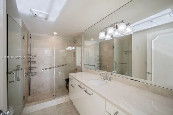 a bathroom with a sink a large mirror and shower