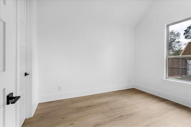 a view of a room that has wooden floor and a window